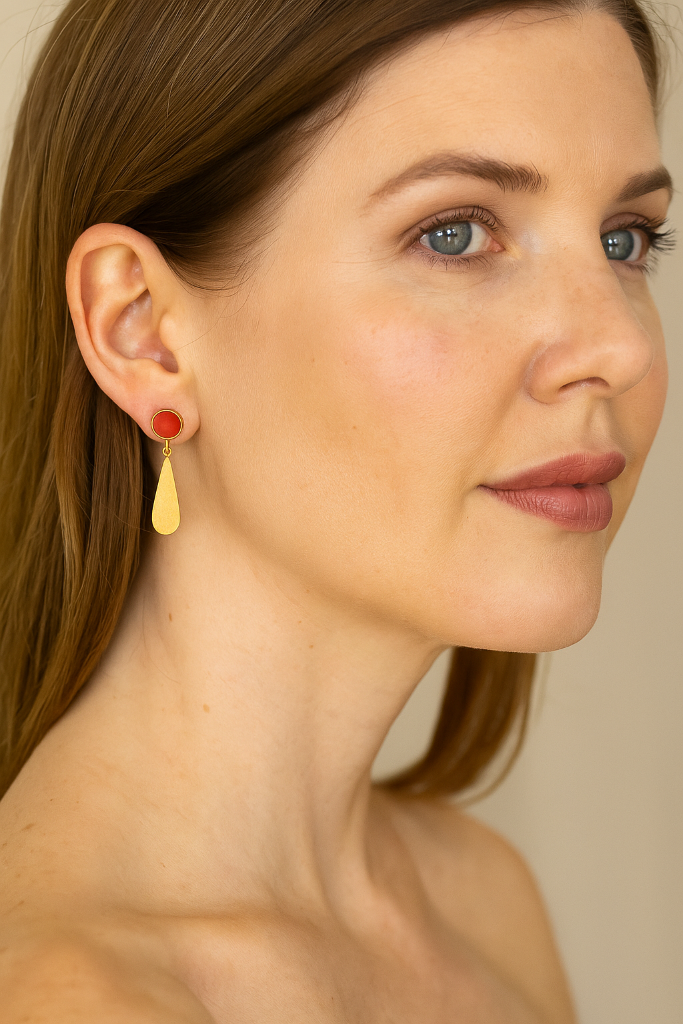 Woman wearing gold earrings with a neutral background